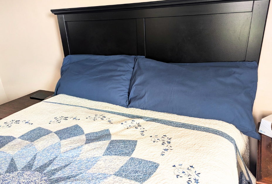 A made bed with blue pillows and quilt